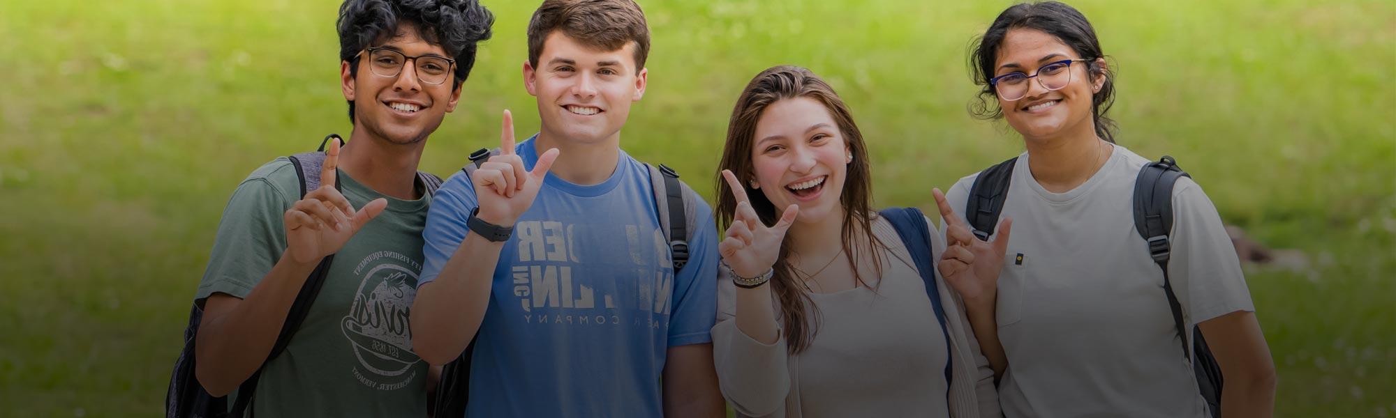 Four smiling students holding the J sign